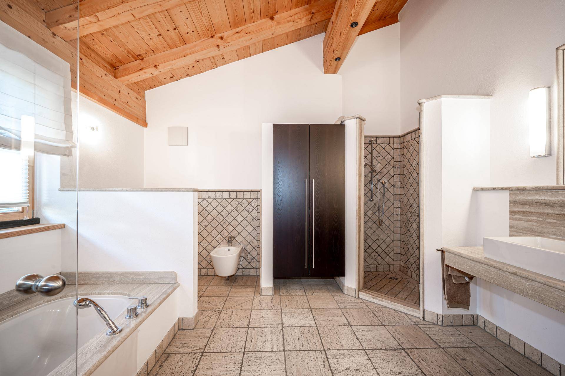 Geräumiges Badezimmer mit Badewanne, begehbarer Dusche, Bidet und Holzbalkendecke.