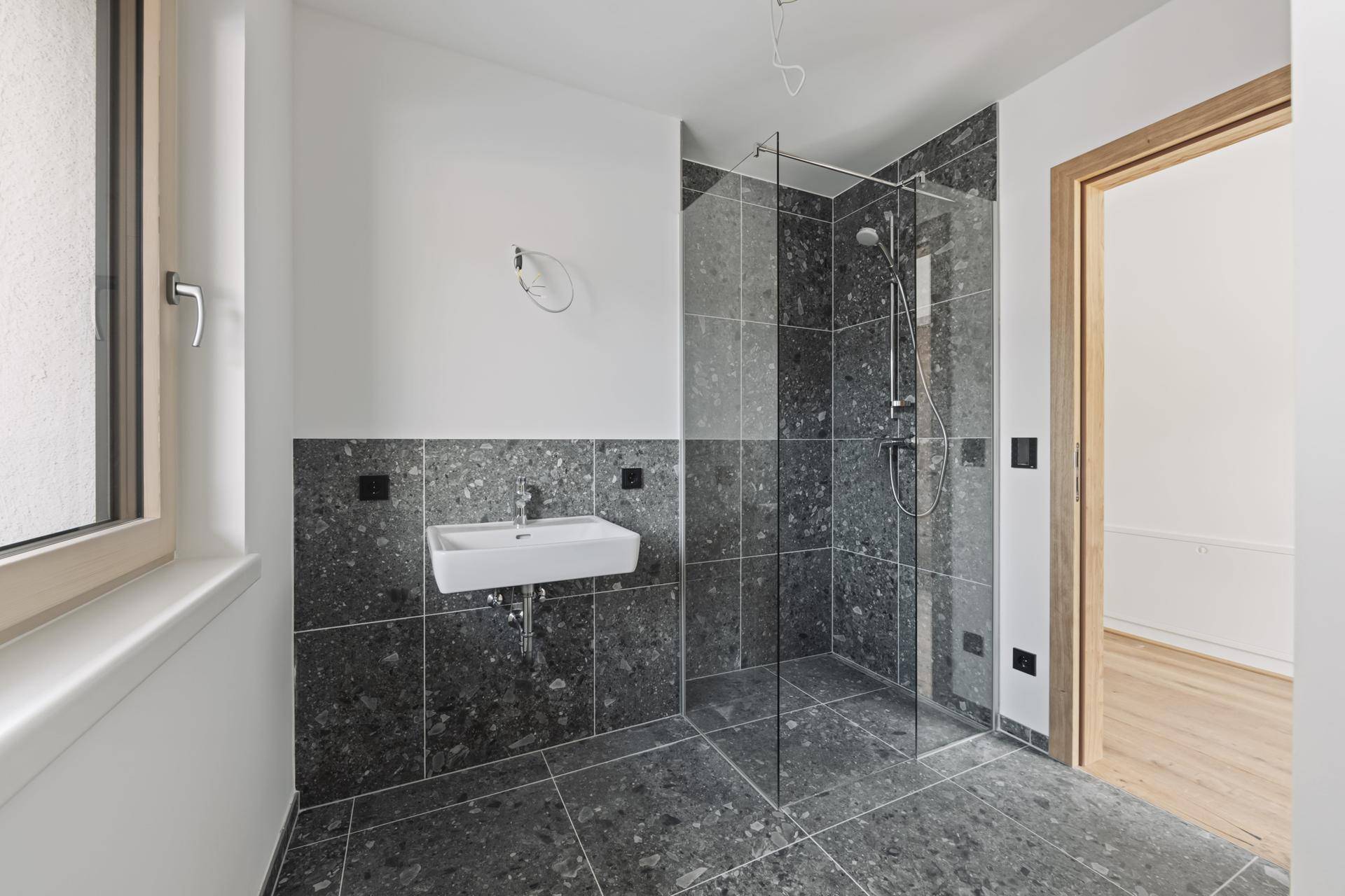 Modernes Badezimmer mit begehbarer Dusche, Waschbecken und Fenster für natürliches Licht.
