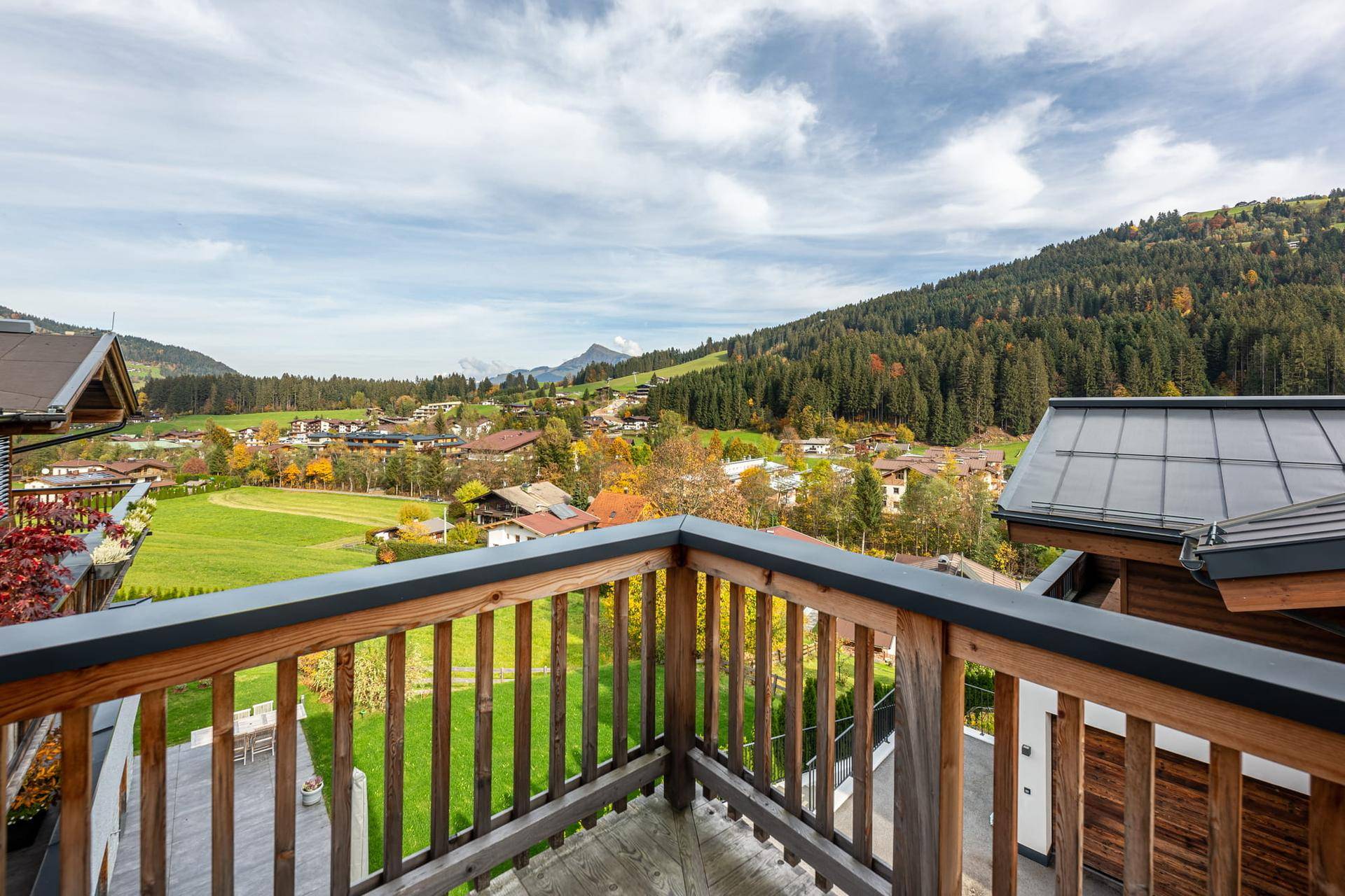 Balkon mit Holzelementen und weitem Blick über die grüne Landschaft und Berge.