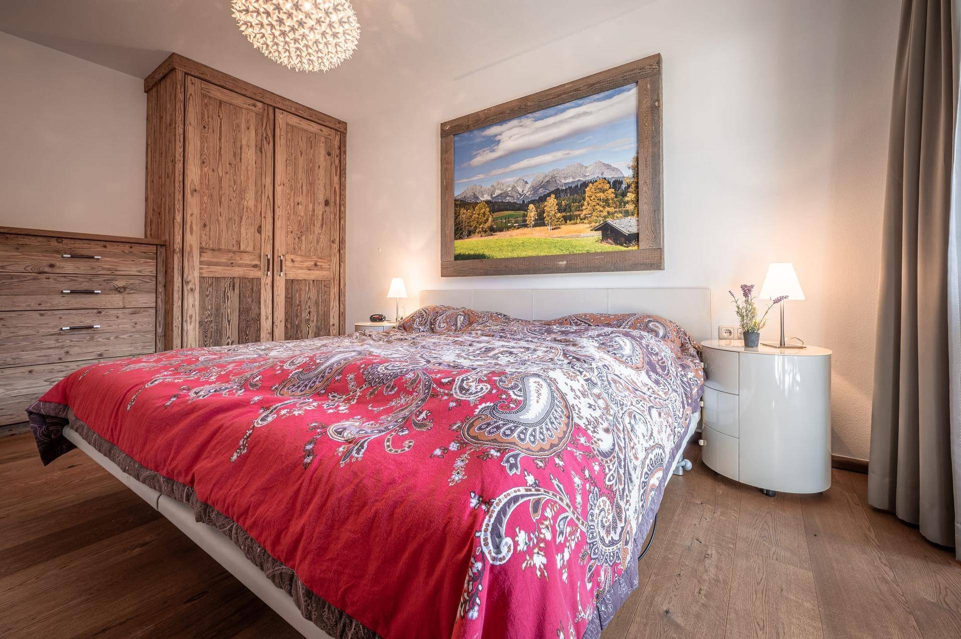 Helles Schlafzimmer mit Doppelbett, Holzkleiderschrank und großem Wandbild.