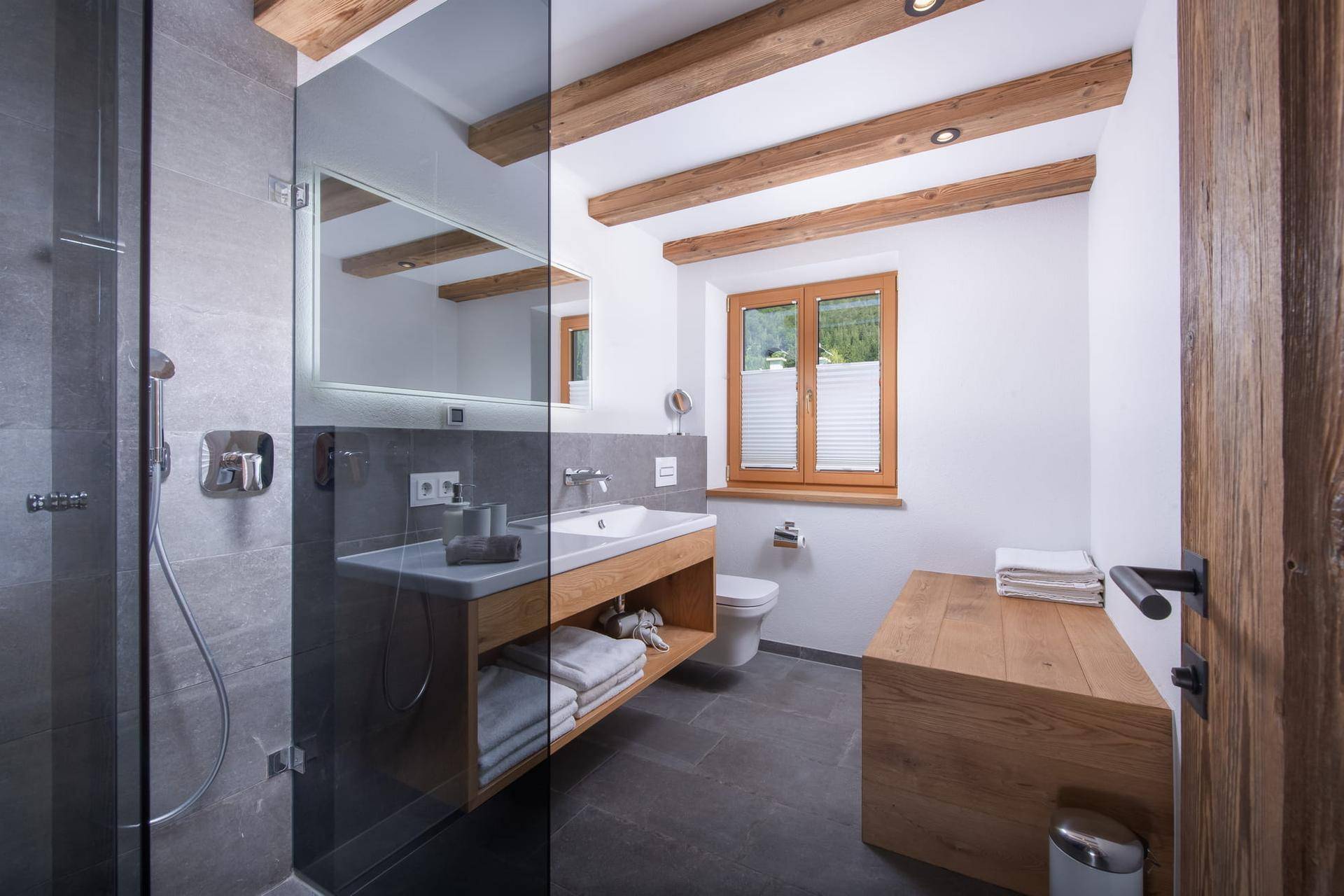 Modernes Badezimmer mit begehbarer Dusche, Holzwaschtisch und Fenster für Tageslicht.
