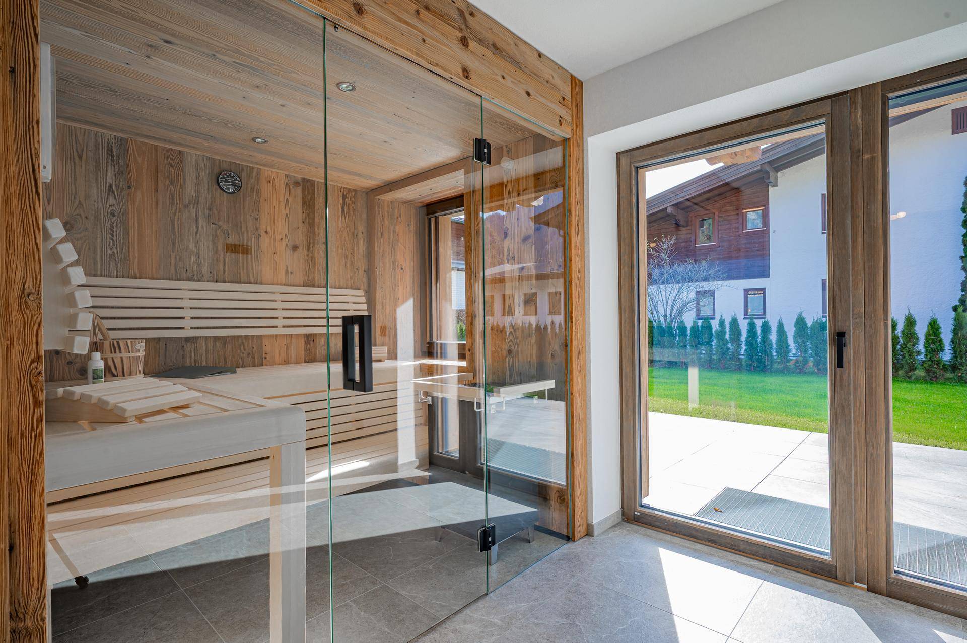 Moderne Sauna mit Holzverkleidung und Glasfront, direktem Zugang zum Garten.