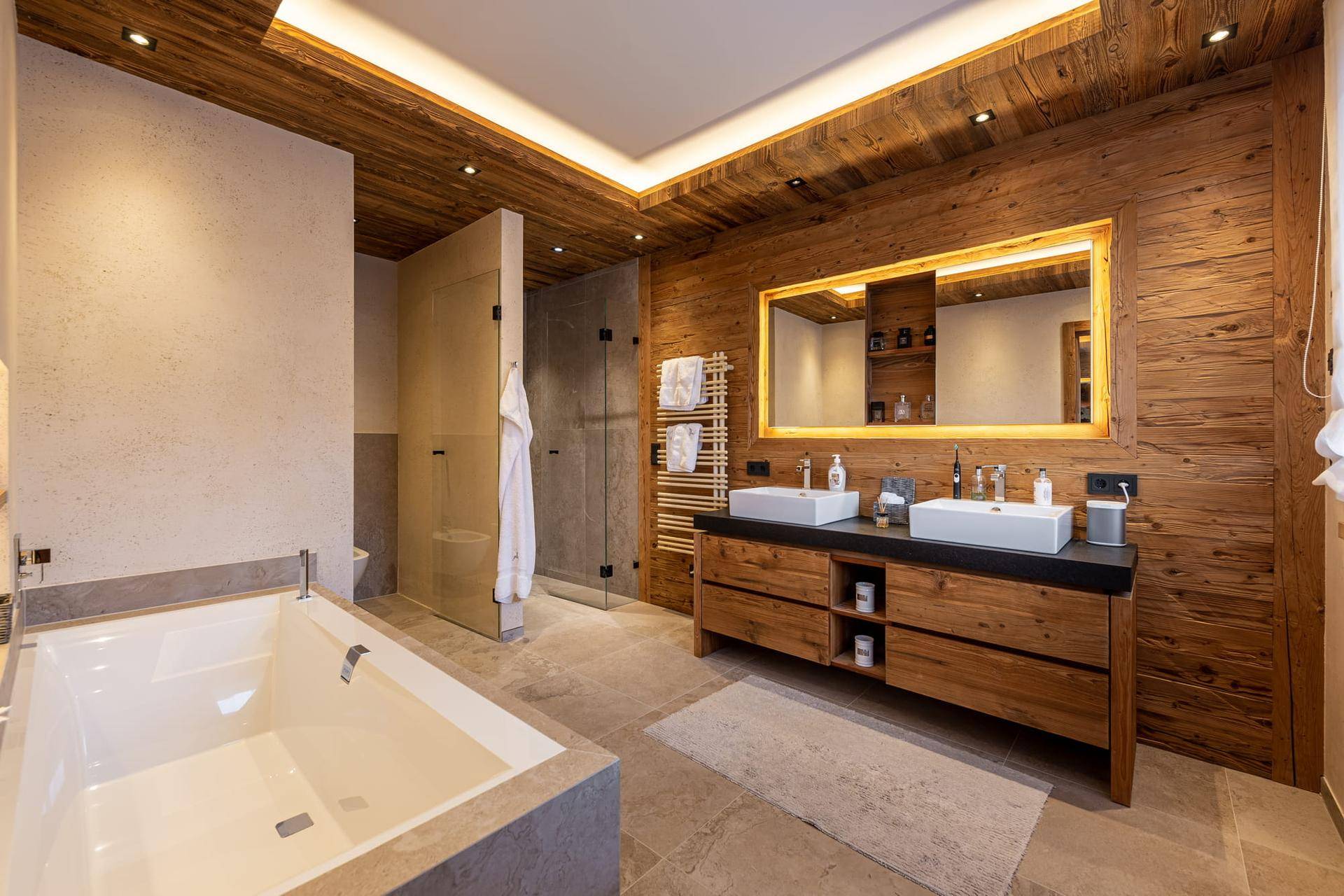 Luxuriöses Badezimmer mit Holzwänden, Doppelwaschbecken, Badewanne und begehbarer Dusche.