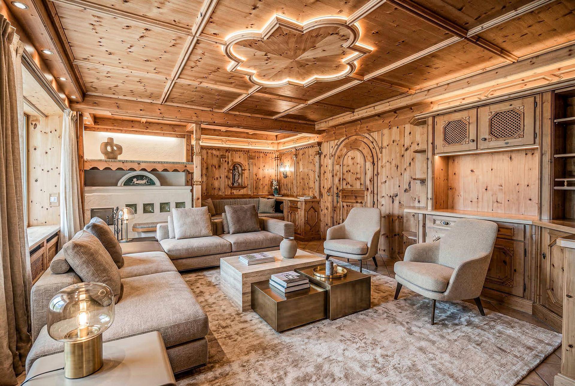 Gemütliches Wohnzimmer im alpinen Stil mit Holztäfelung, Kassettendecke und indirekter Beleuchtung.