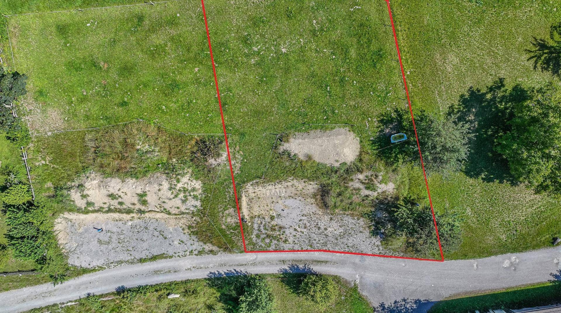 Luftaufnahme eines Grundstücks mit roten Grenzlinien und angrenzender Zufahrtsstraße.