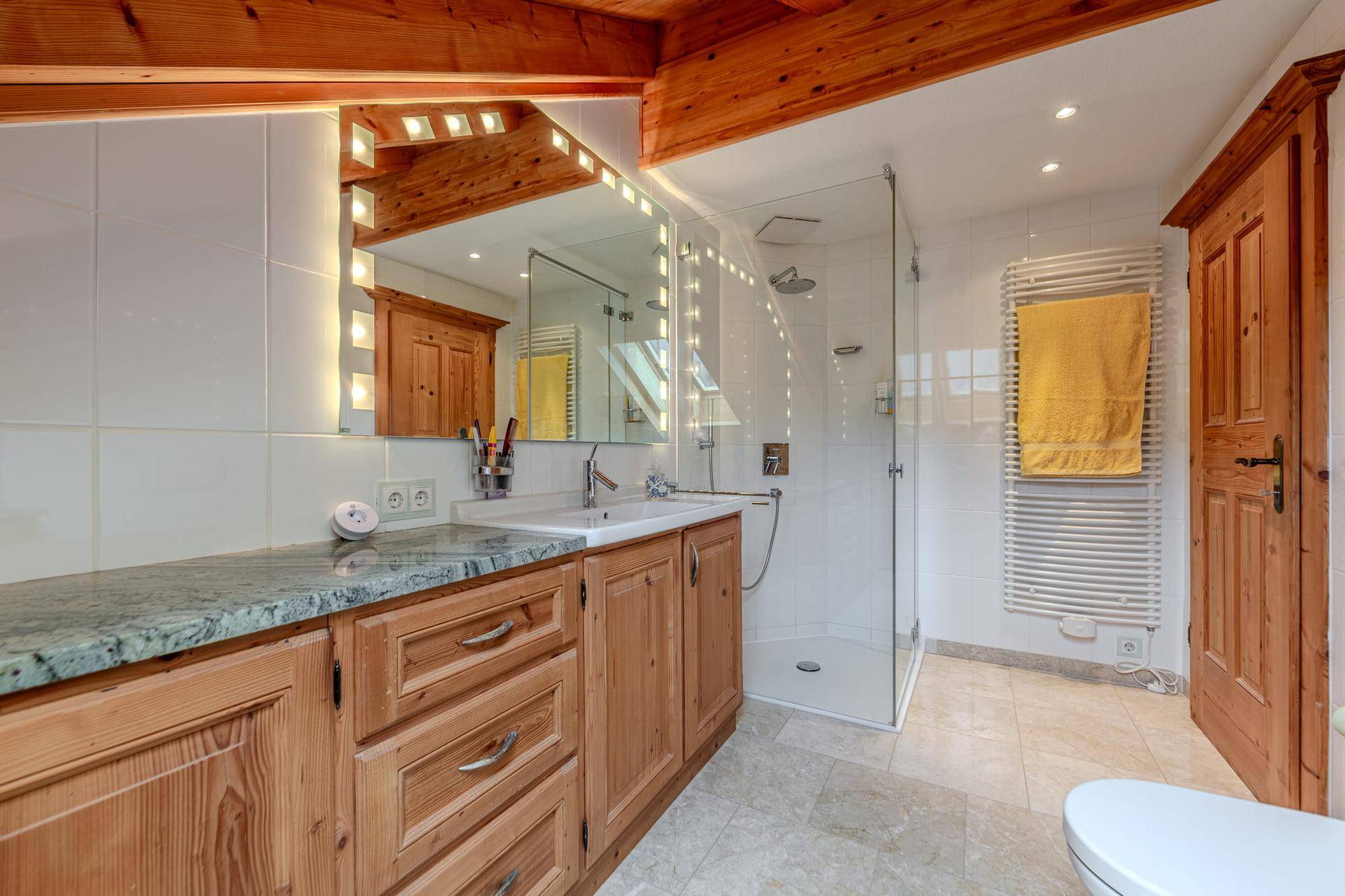 Modernes Badezimmer mit begehbarer Dusche, Holzwaschtisch und beheiztem Handtuchhalter.