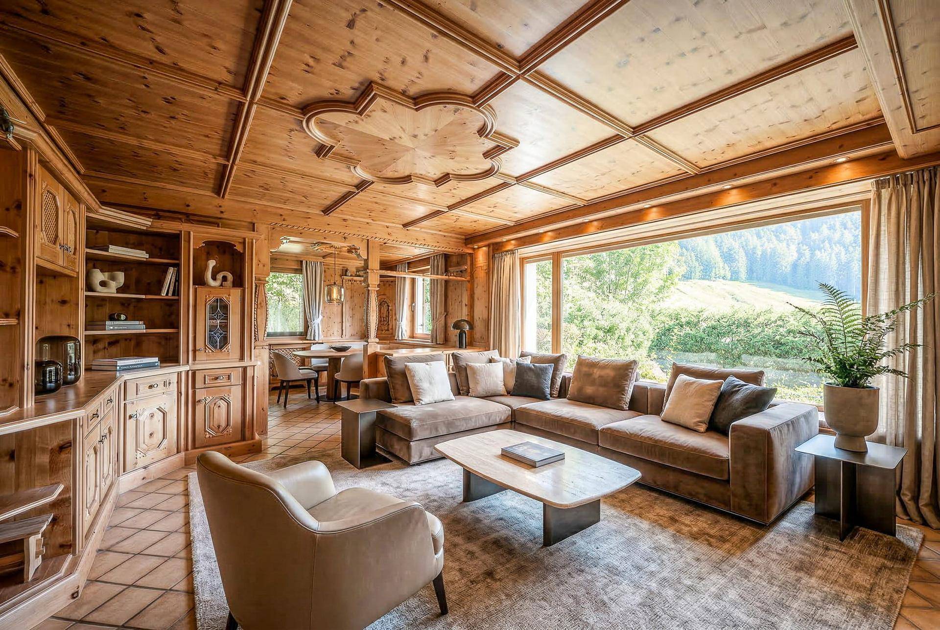 Geräumiger Wohnbereich mit bequemen Sofas, Holzeinbauten und weitem Blick ins Grüne.