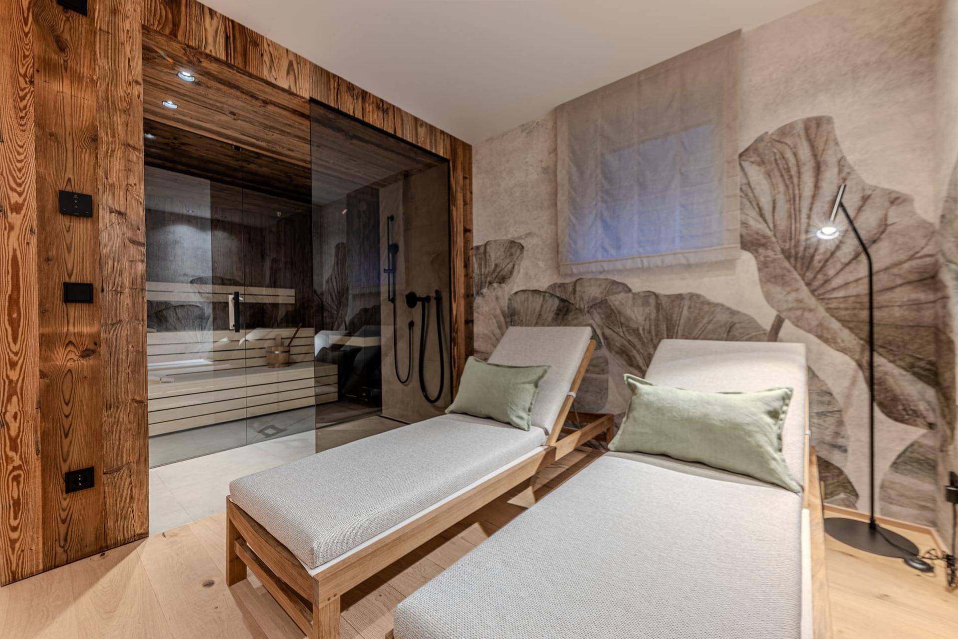 Entspannungsbereich mit Sauna, bequemen Liegen und dekorativer Wandgestaltung.