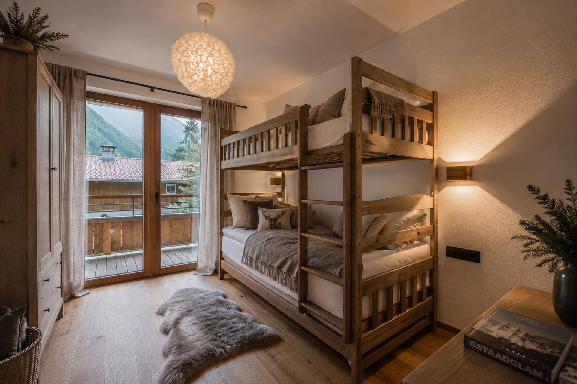 Kinderzimmer mit Etagenbett aus Holz, Holzboden und Zugang zu einem Balkon mit Bergblick.