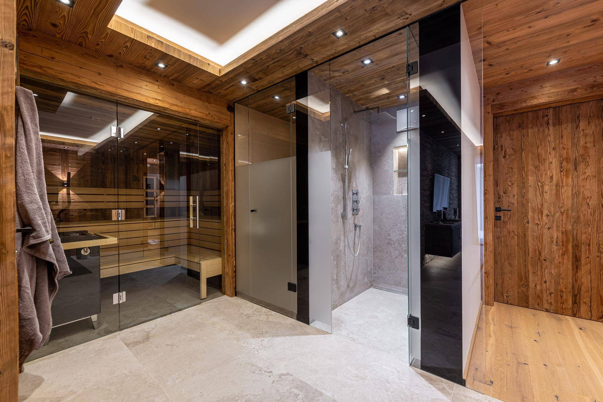 Exklusiver Wellnessbereich mit Sauna, großer Dusche und Holzelementen.