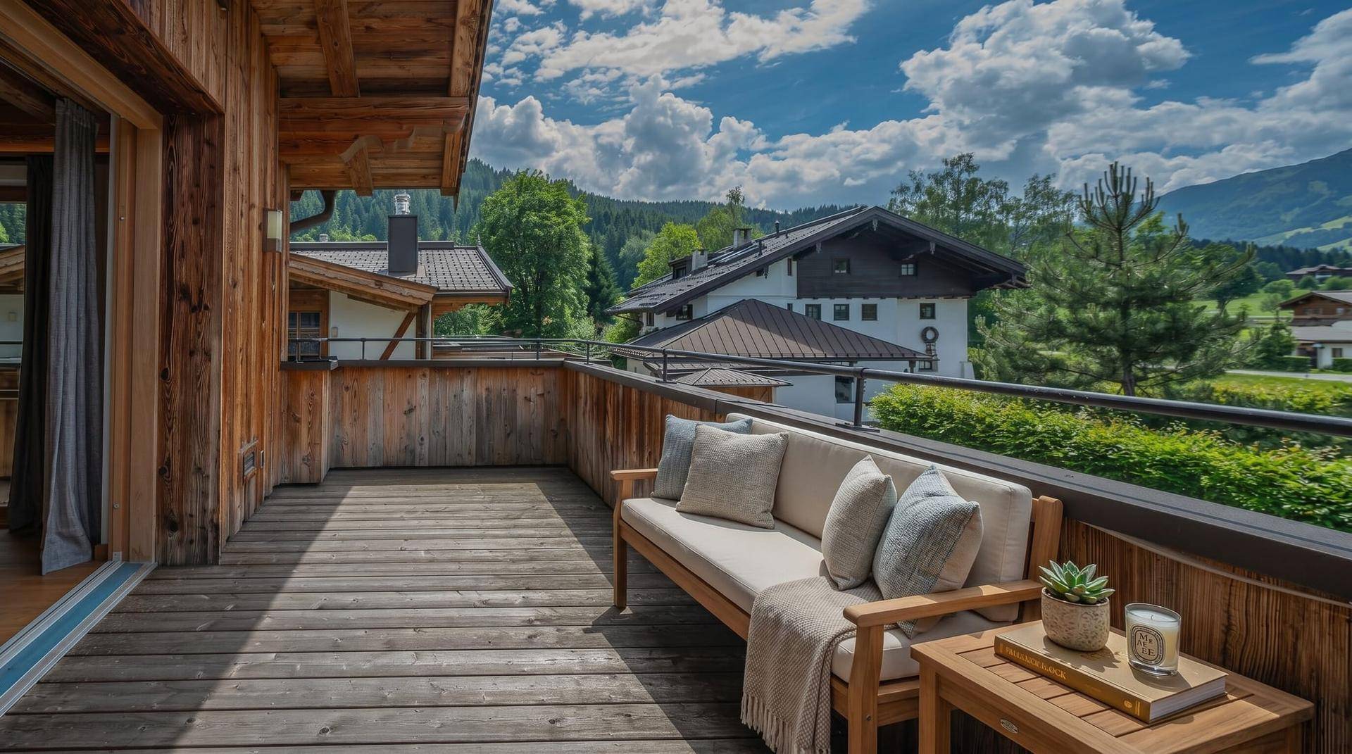Geräumiger Holzbalkon mit Sitzgelegenheiten und weitem Blick auf die Berglandschaft.