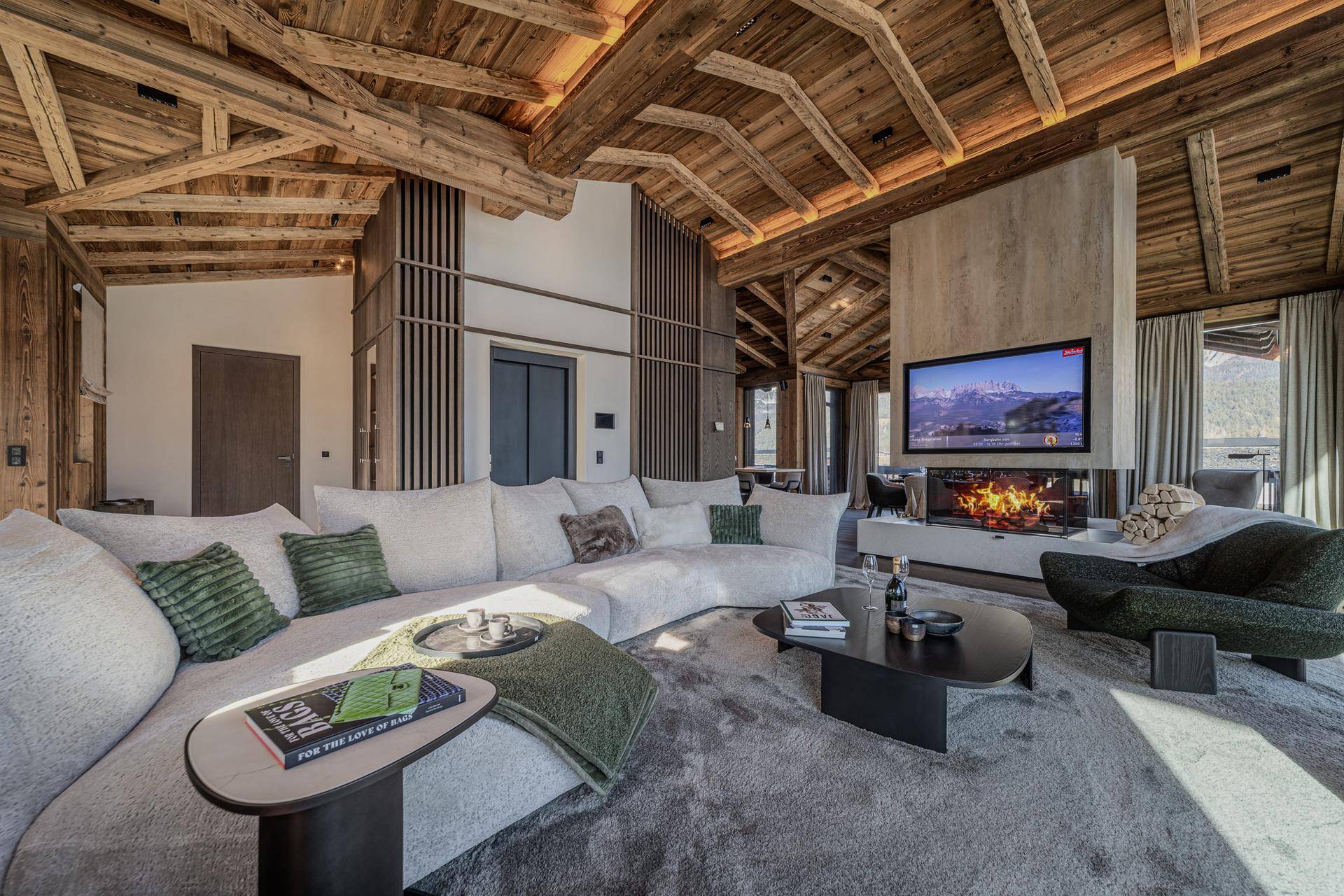 Geräumiges Wohnzimmer mit großem Ecksofa, modernem Kamin und Holzbalkendecke.