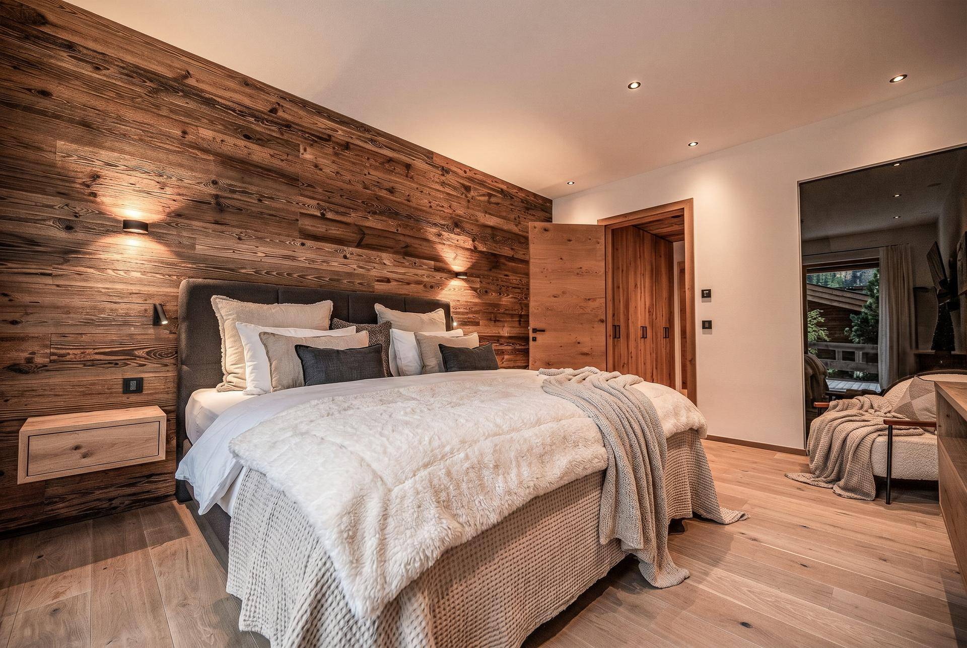 Modernes Schlafzimmer mit Holzwandverkleidung, großem Bett und hellem Holzfußboden.
