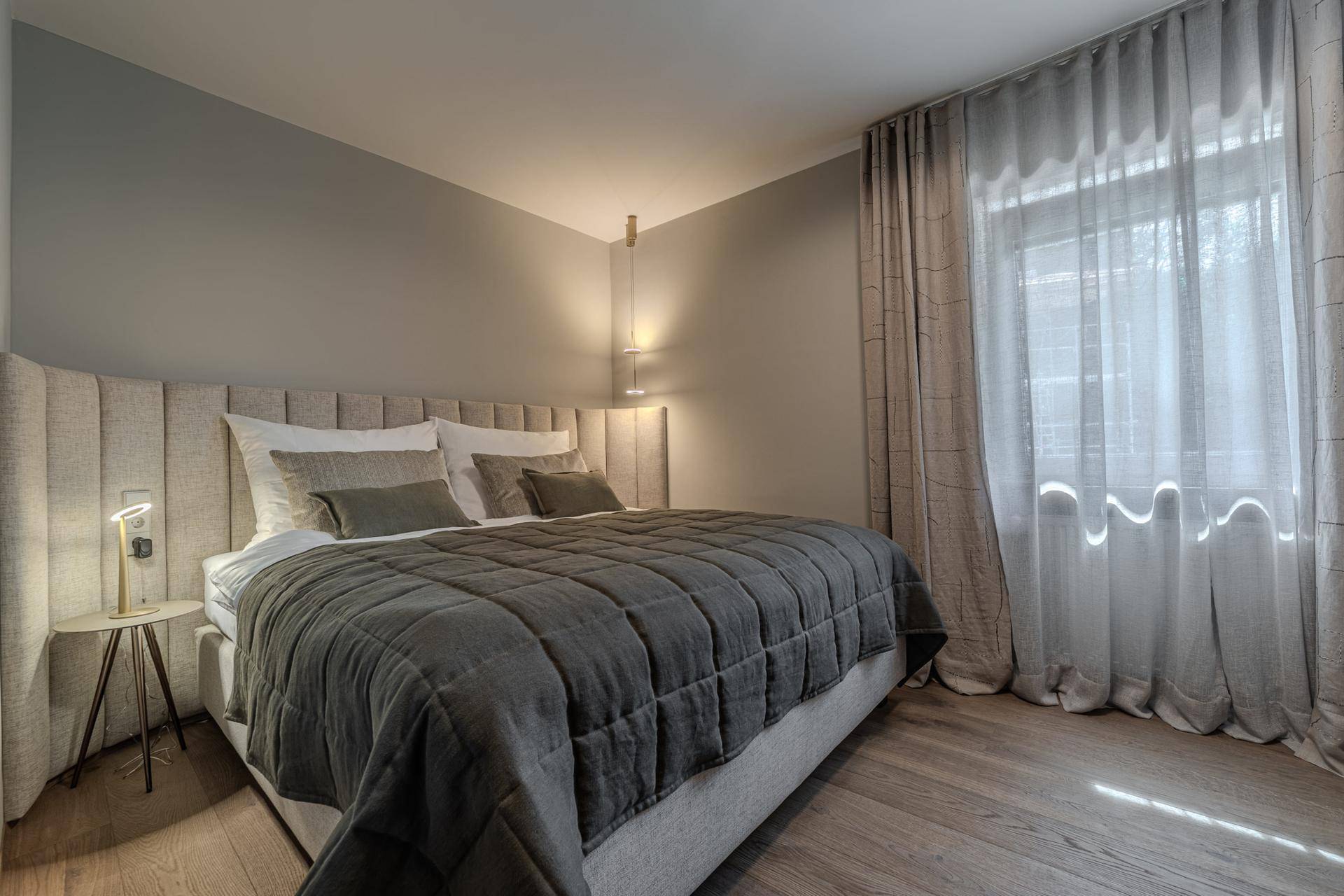Gemütliches Schlafzimmer mit großem Doppelbett, weichen Vorhängen und Holzboden.