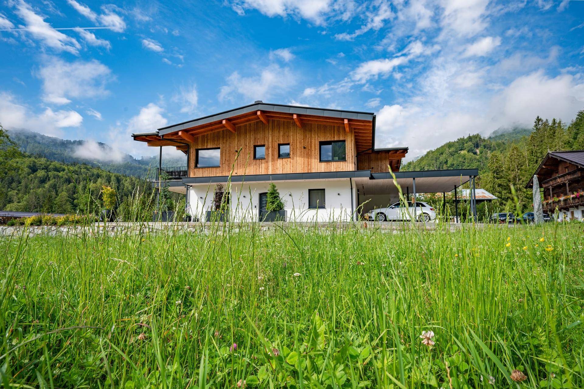 Modernes Einfamilienhaus in Holz- und Massivbauweise mit Carport und Bergblick.