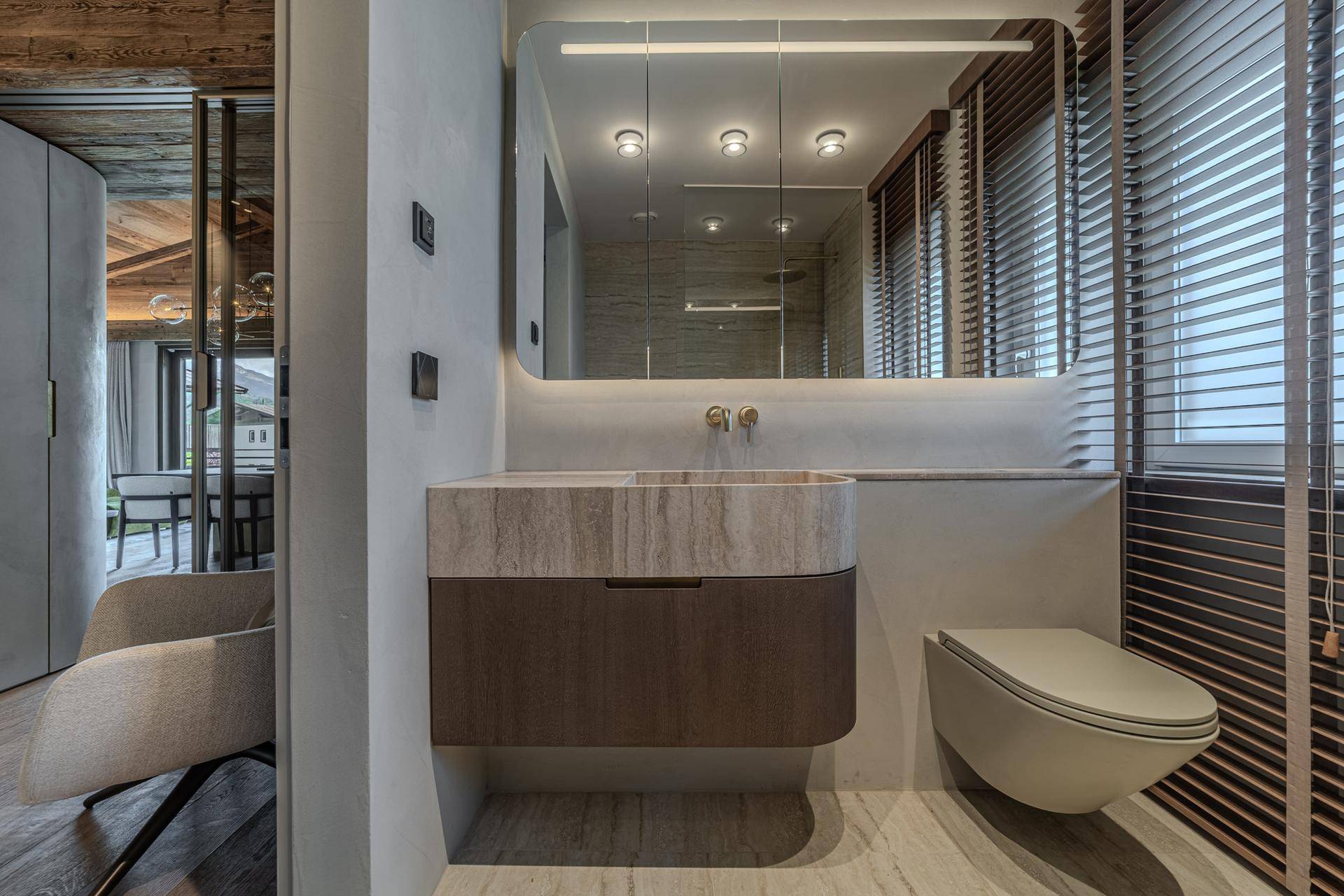 Modernes Badezimmer mit elegantem Waschtisch, Wand-WC und großer Spiegelfläche.
