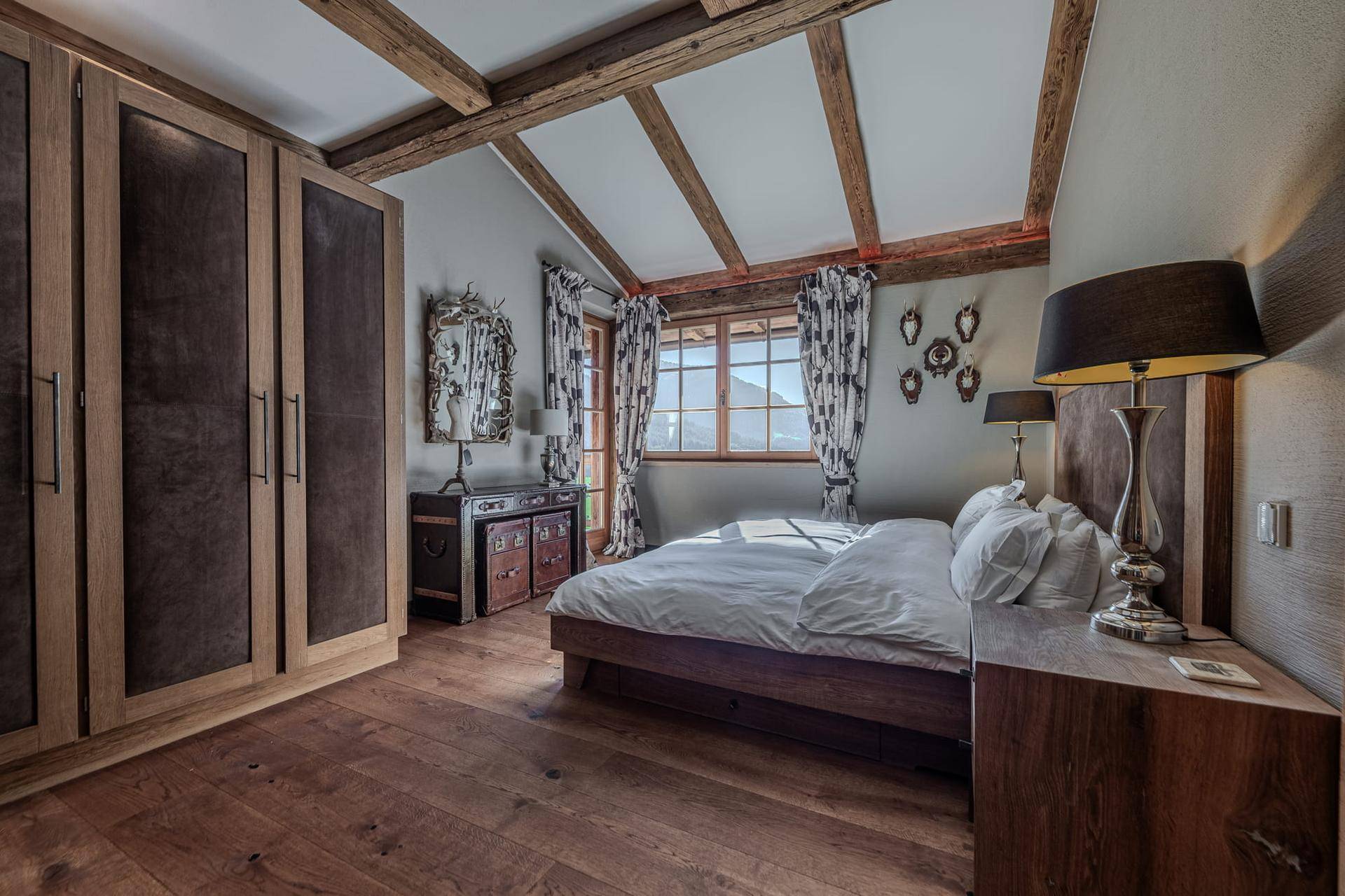 Elegantes Schlafzimmer im Dachgeschoss mit Holzbalken, Einbauschränken und Bergblick.