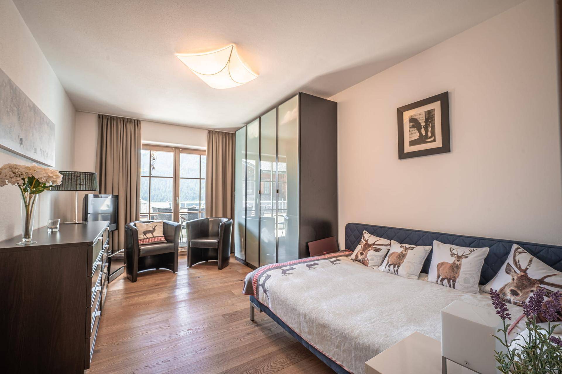 Gemütliches Schlafzimmer mit Einzelbett, Kleiderschrank und Blick auf die verschneite Landschaft.