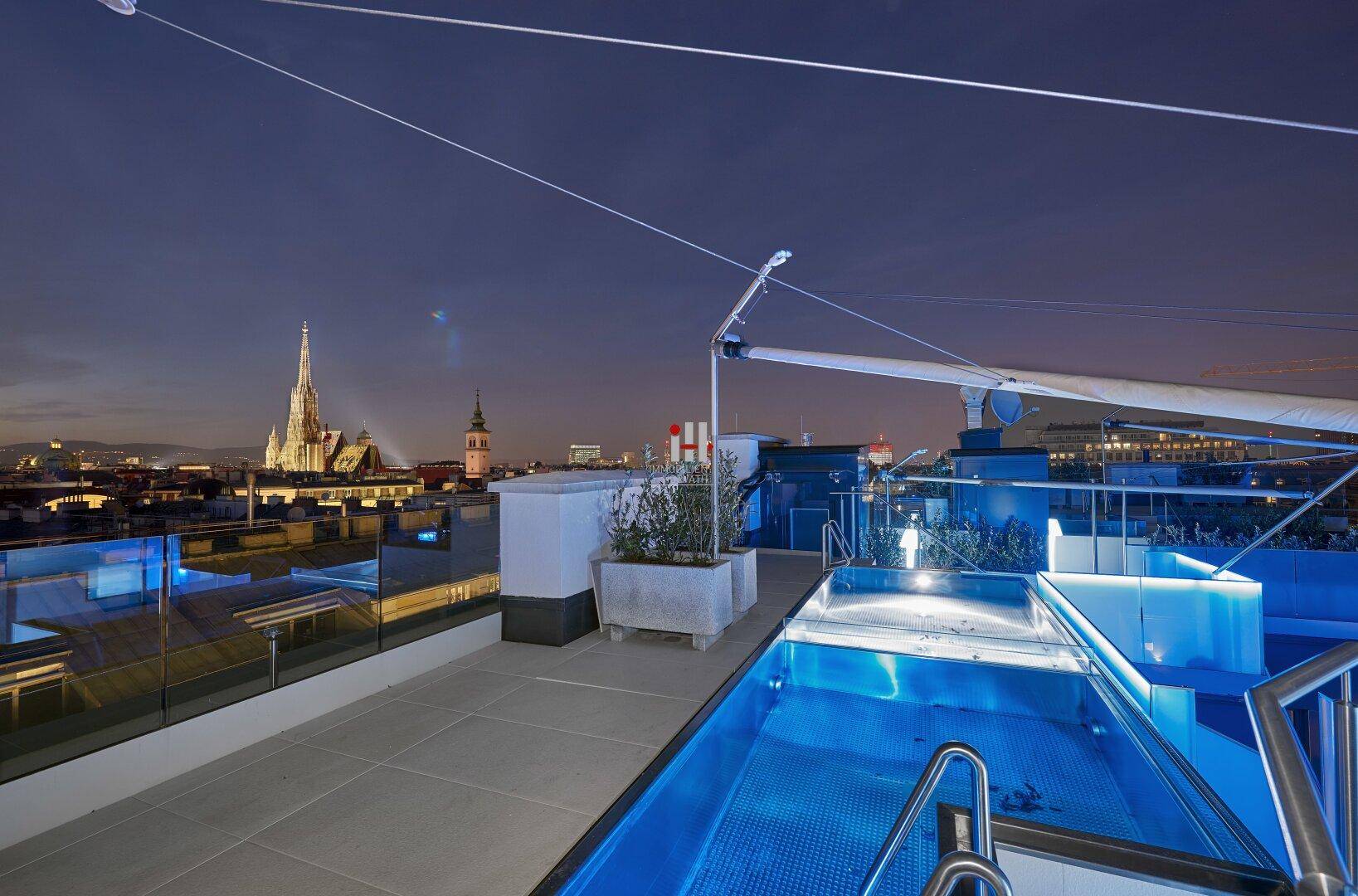 Dachterrasse mit Pool und atemberaubendem Blick auf die beleuchtete Stadtkulisse bei Nacht.
