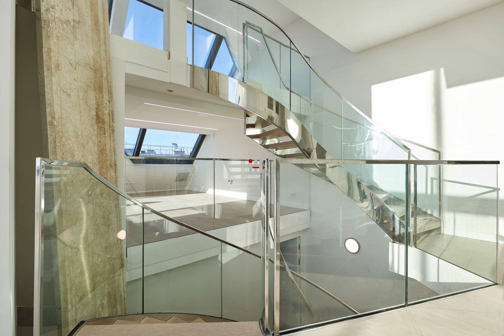 Elegante Treppe mit Glasgeländer und Holzelementen, die verschiedene Ebenen des Penthouses verbindet.
