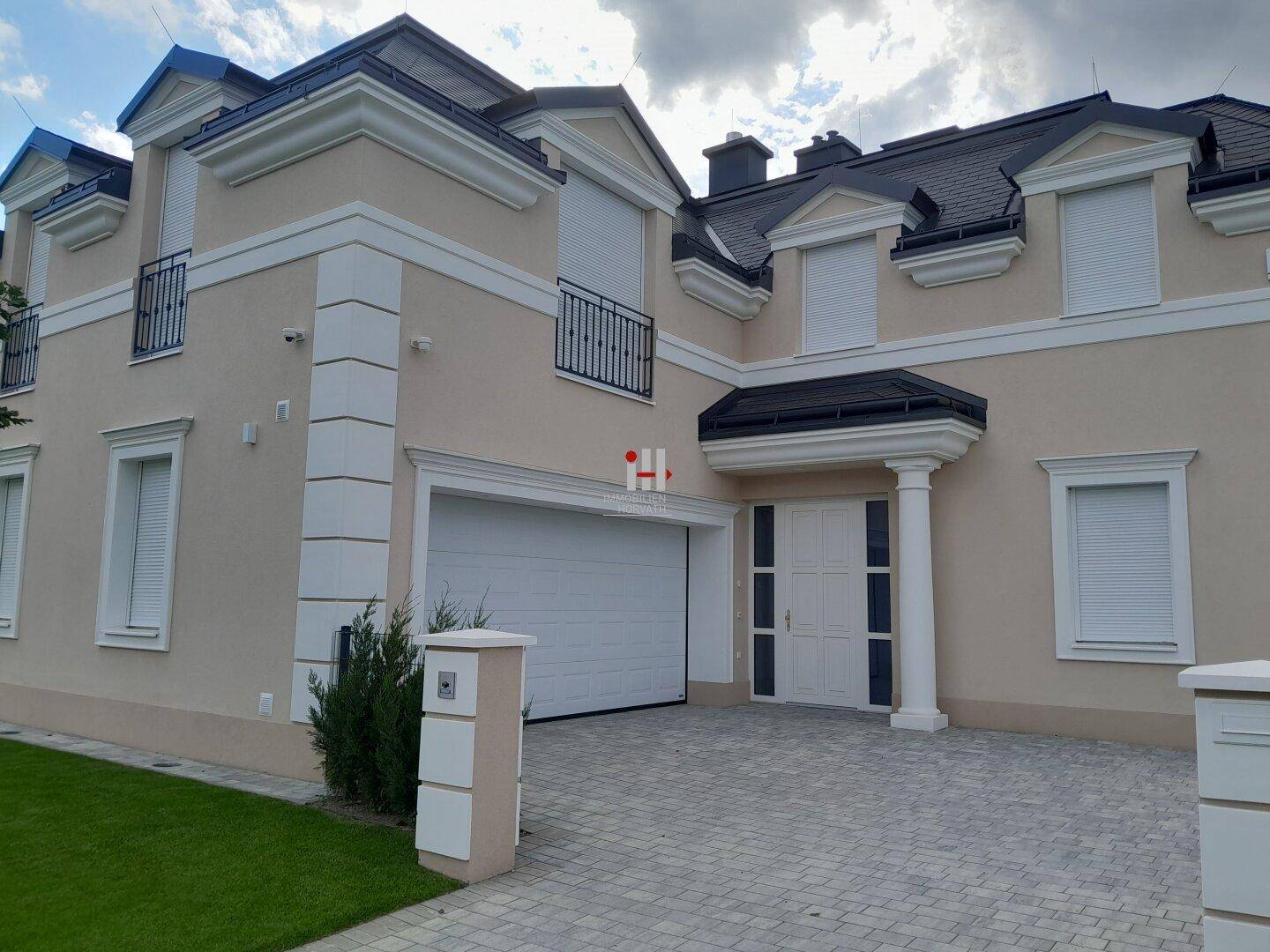 Elegante Hausfassade mit Doppelgarage, Rollläden und klassischer Architektur.