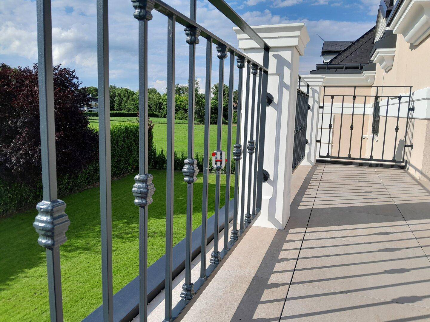 Balkon mit elegantem Geländer und weitem Blick über die grüne Landschaft.