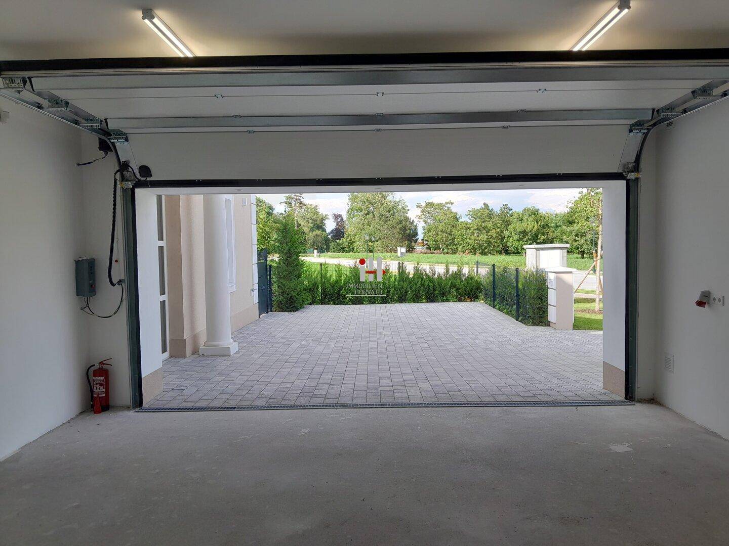 Geräumige Garage mit offenem Tor und Blick auf die gepflasterte Einfahrt.