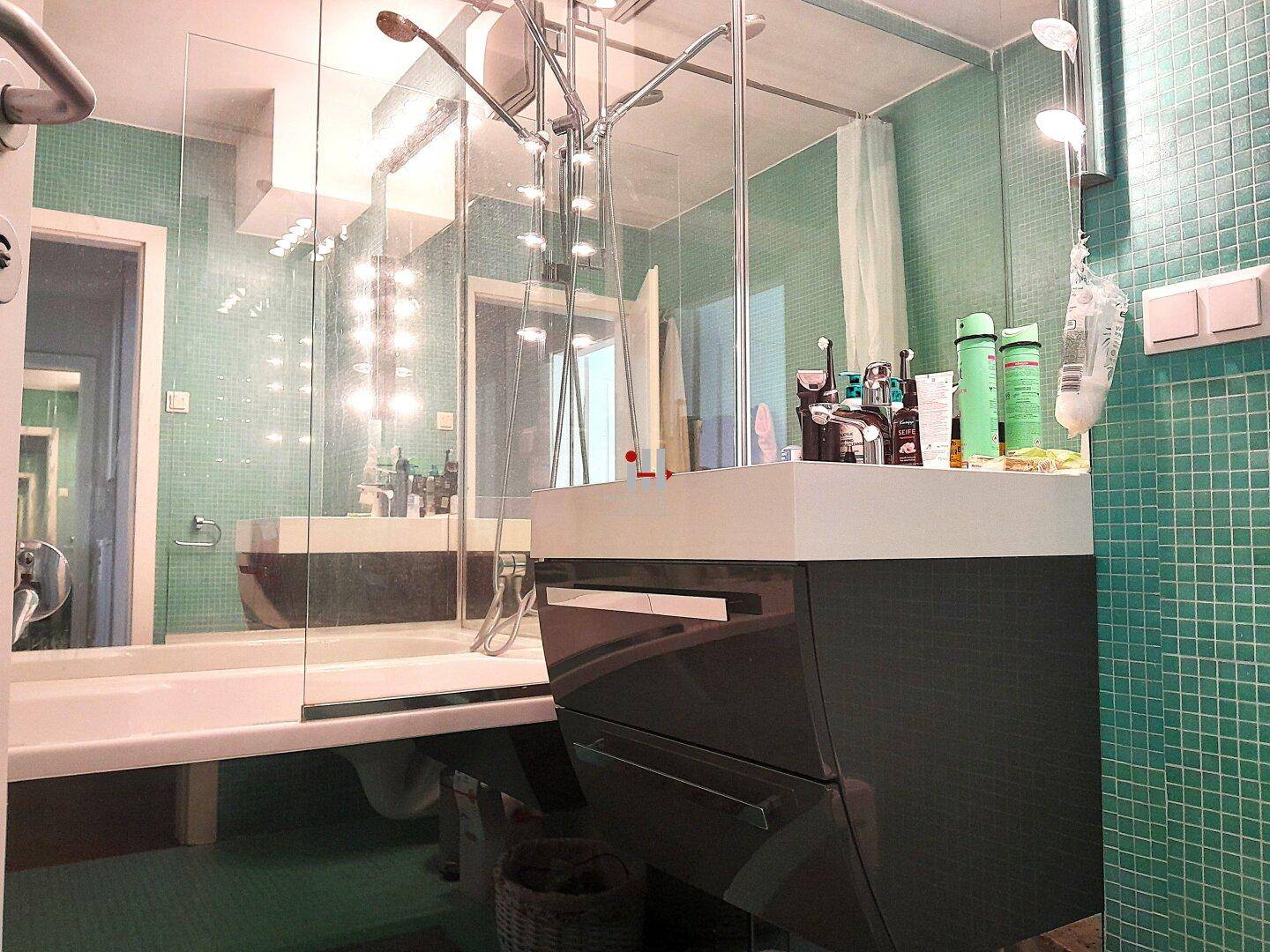 Modernes Badezimmer mit türkisfarbenen Fliesen, großem Spiegel und begehbarer Dusche.