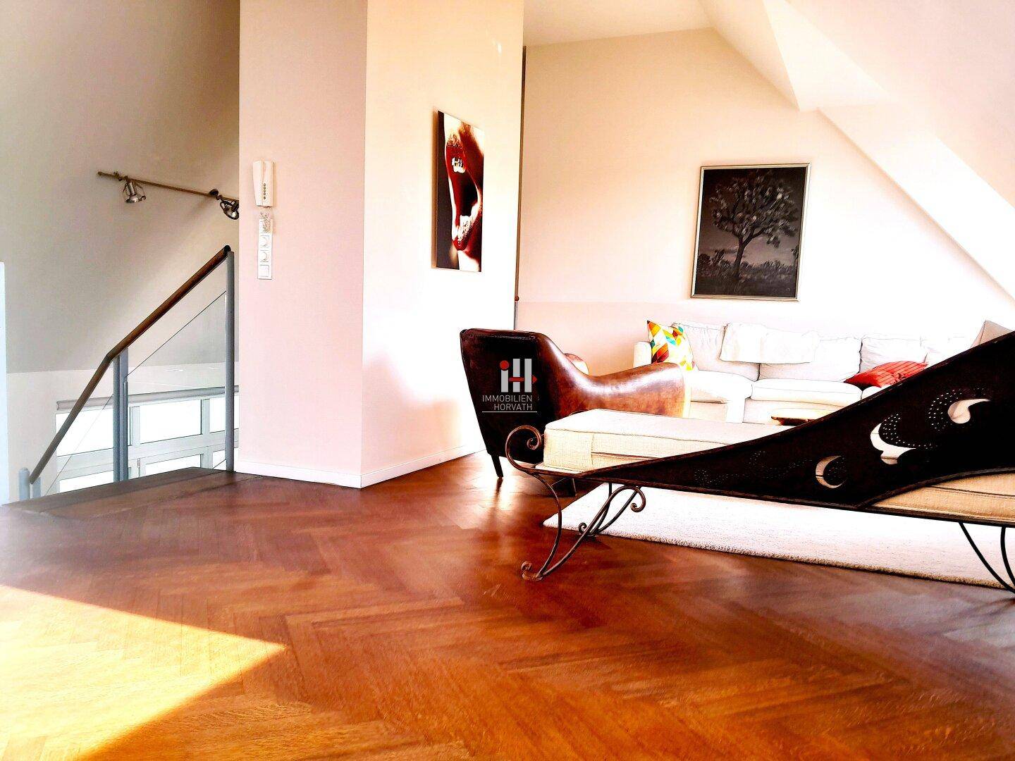 Geräumiger Wohnbereich mit Fischgrätparkett, moderner Einrichtung und Zugang zur Treppe.