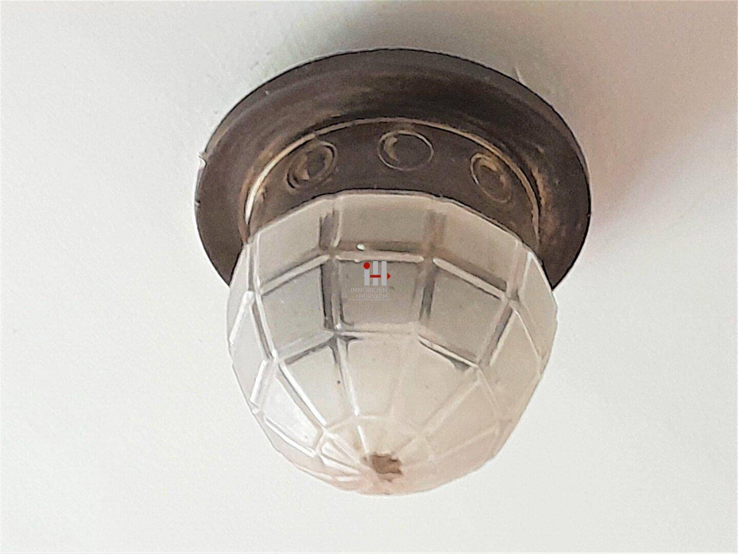 Detailaufnahme einer klassischen Deckenleuchte mit strukturiertem Glas und Metallfassung.