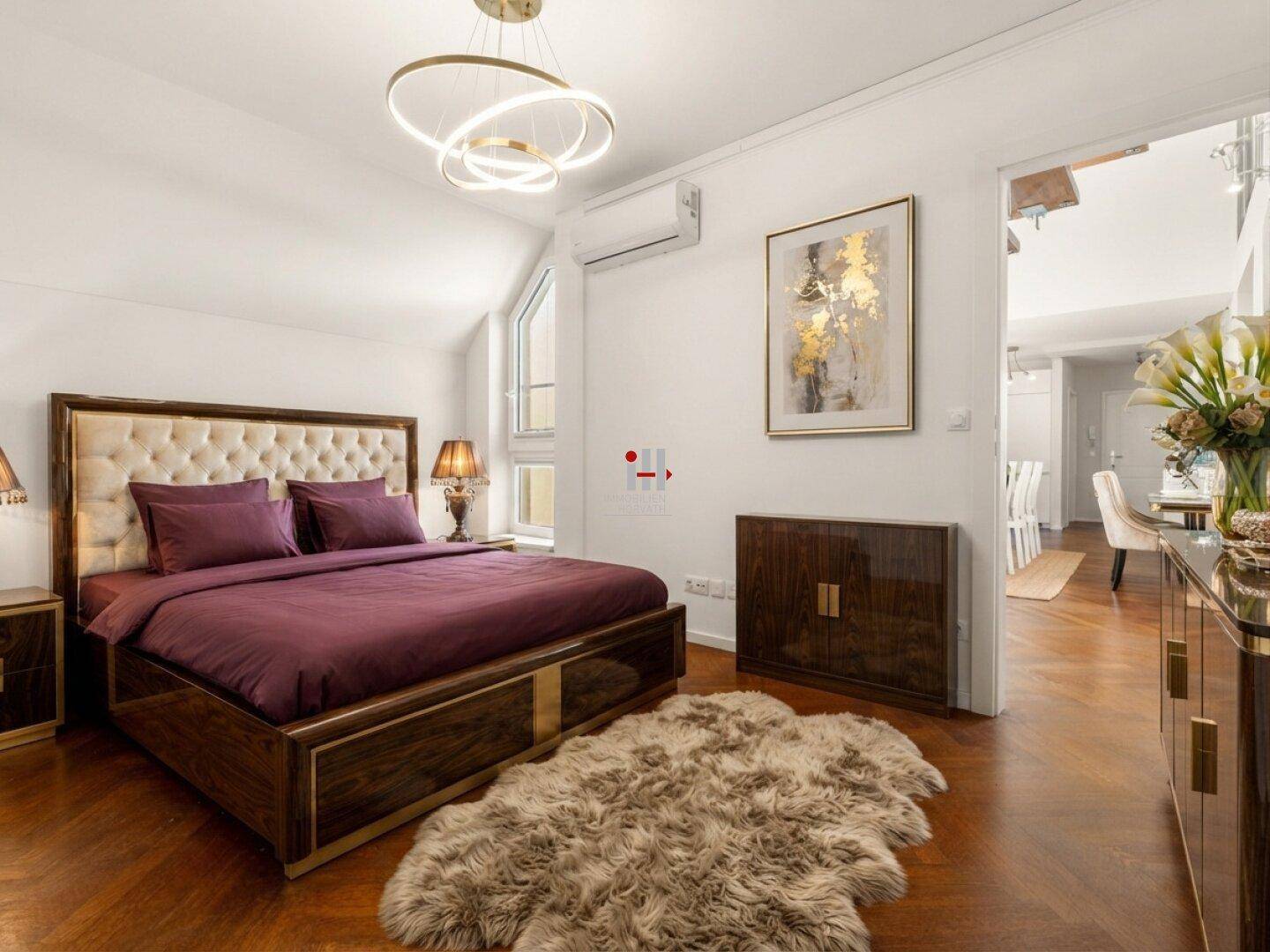 Elegantes Schlafzimmer mit Holzboden, gepolstertem Bett und Zugang zum Essbereich.