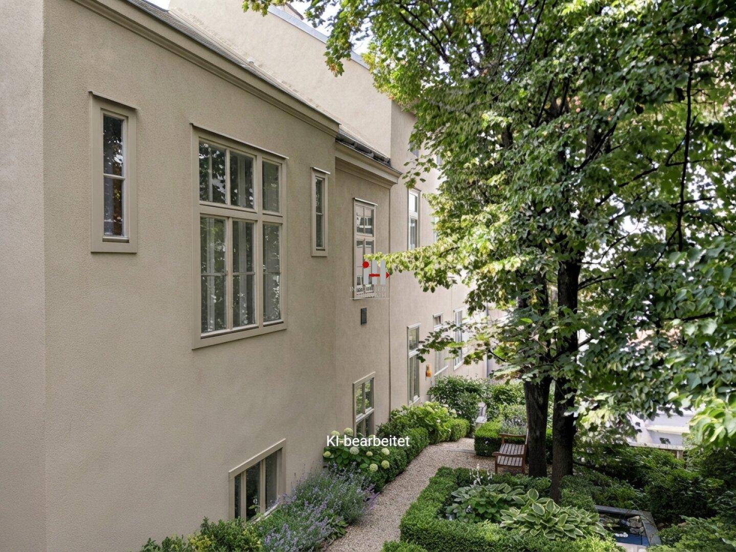 Ruhiger Innenhofgarten mit gepflegten Beeten, Bäumen und einem Kiesweg entlang der Gebäudefassade.