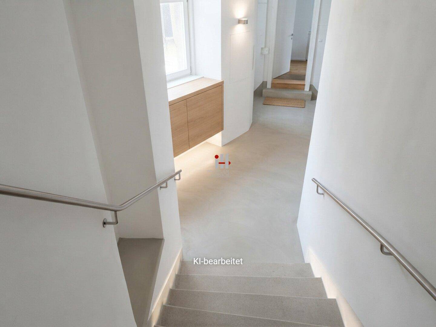 Modernisiertes Treppenhaus mit hellen Wänden, schlichten Handläufen und einem Fenster mit Holzablage.