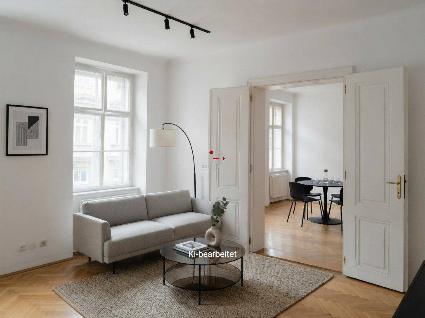 Helles Wohnzimmer mit Fischgrätparkett, modernem Sofa und Zugang zu einem Essbereich durch Flügeltüren.
