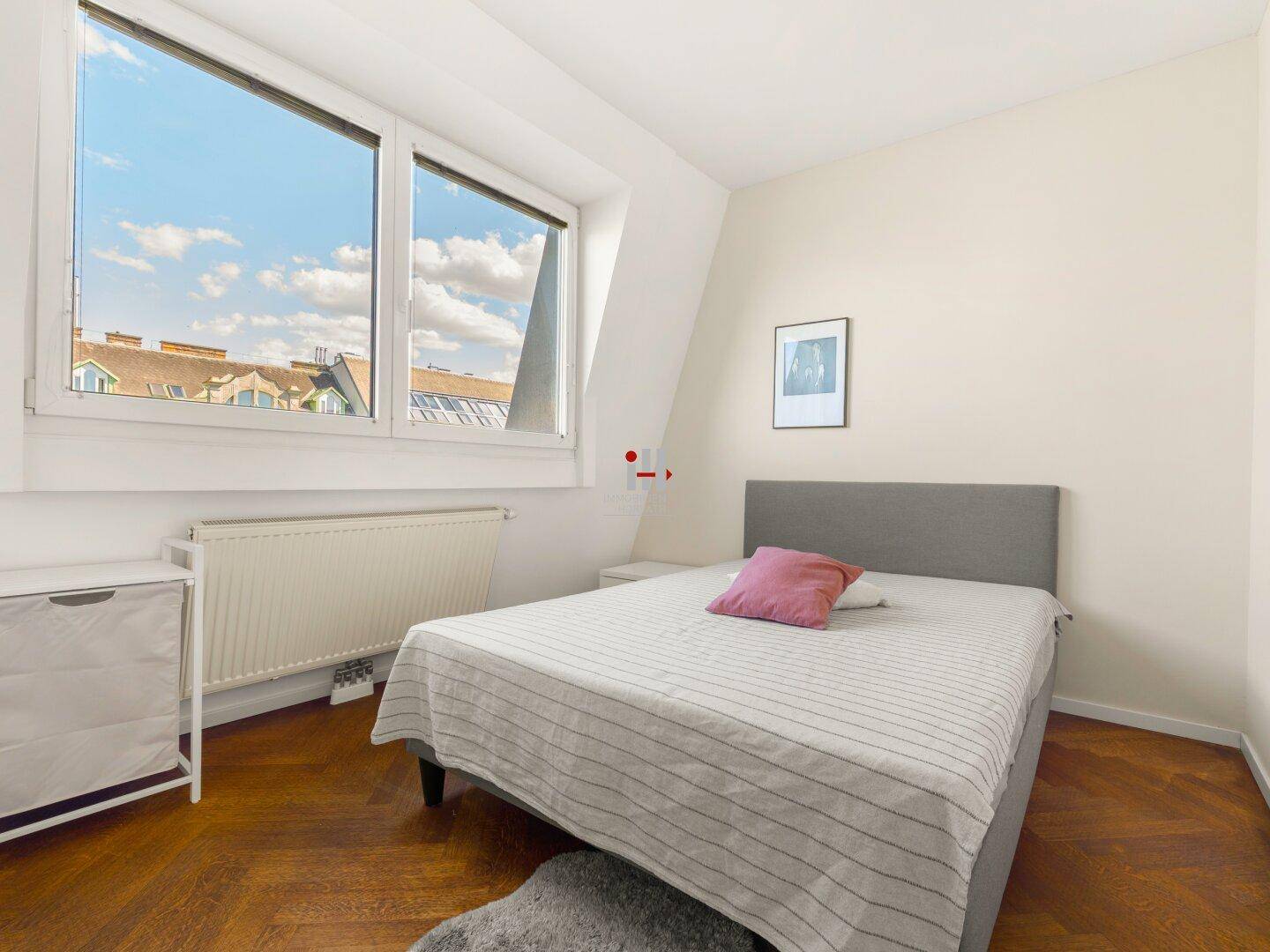 Gemütliches Schlafzimmer mit Holzboden, Dachschräge und weitem Blick über die Dächer.