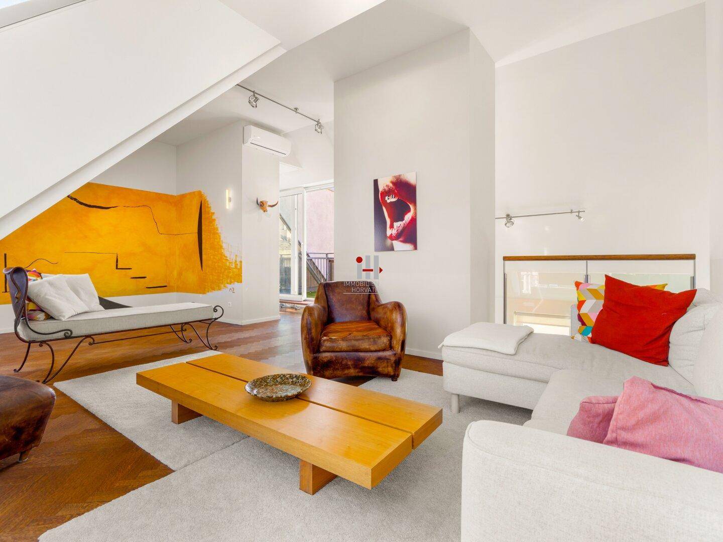 Geräumiges Wohnzimmer mit Parkettboden, moderner Einrichtung und farbiger Wandgestaltung.
