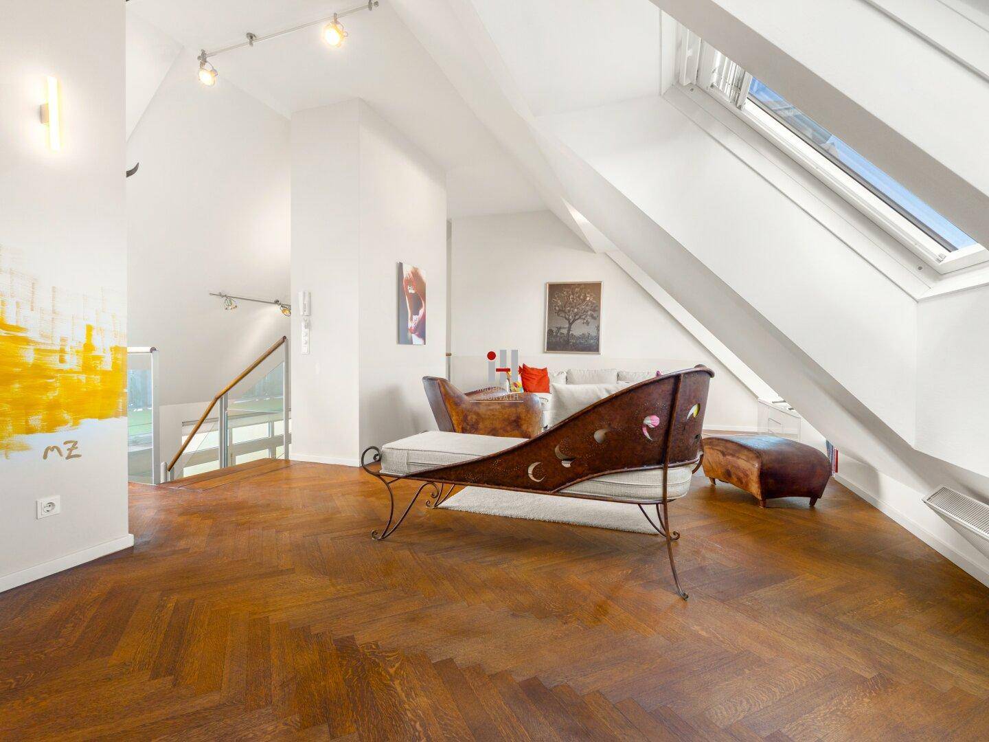 Helles Wohnzimmer mit Dachschrägen, Parkettboden und großen Dachfenstern für viel Licht.