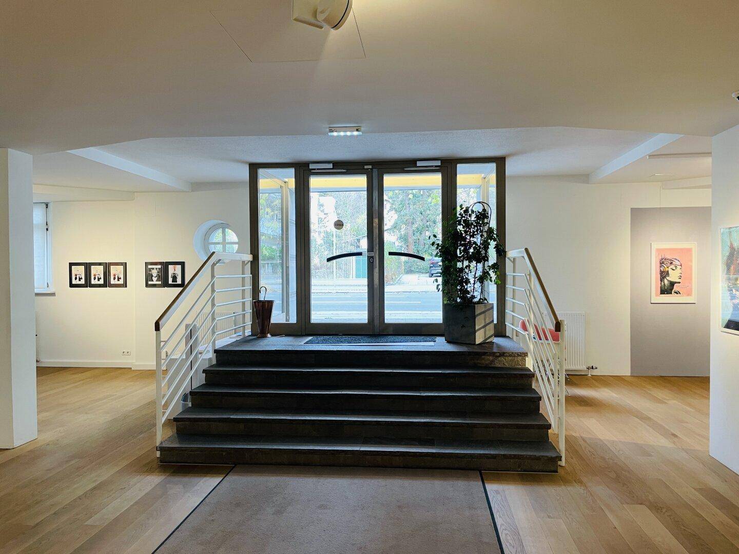 Geräumiger Eingangsbereich mit Treppe, Holzboden und großen Glastüren, die viel Tageslicht hereinlassen.