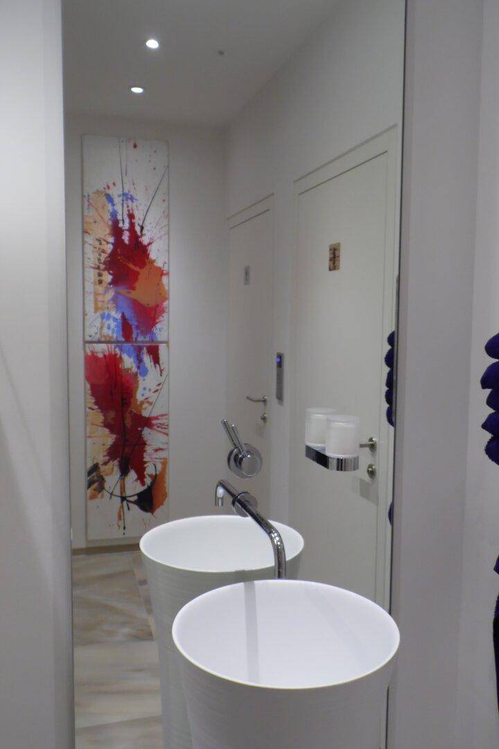 Modernes Badezimmer mit zwei stilvollen Aufsatzwaschbecken und großem Wandspiegel, künstlerisch dekoriert.