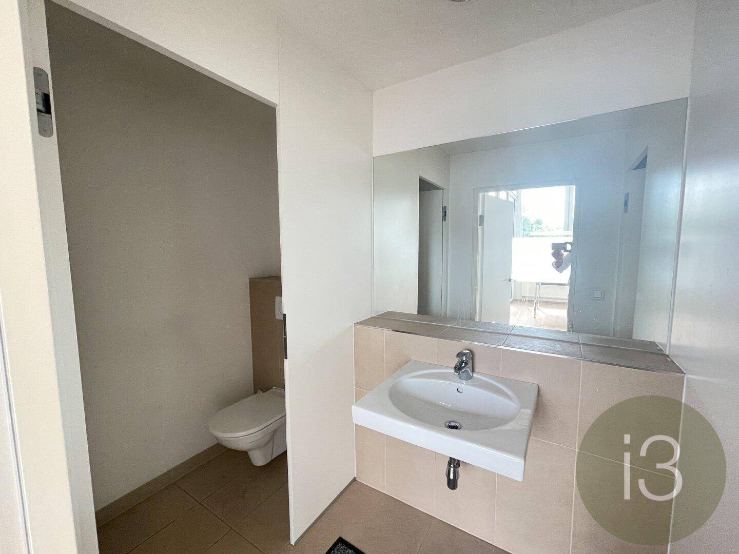 Kleines Badezimmer mit Waschbecken, Spiegel und wandhängender Toilette, funktional und hell gestaltet.