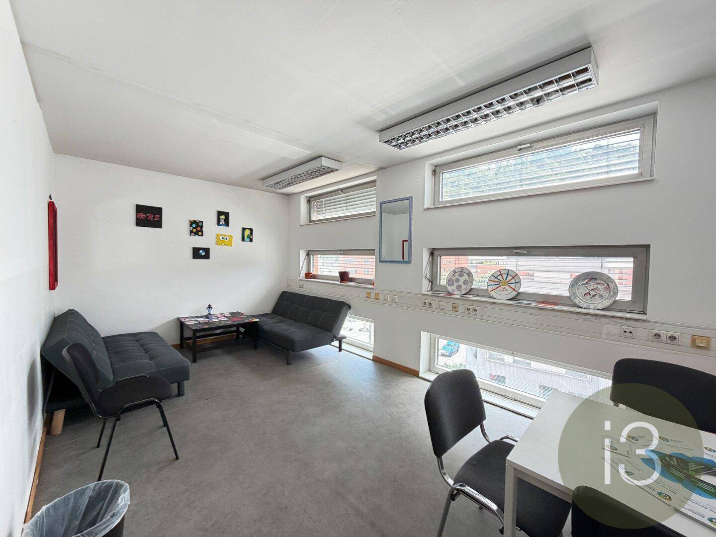 Gemütlicher Aufenthaltsraum mit Sofas, Tischen und Fenstern, ideal für Pausen.