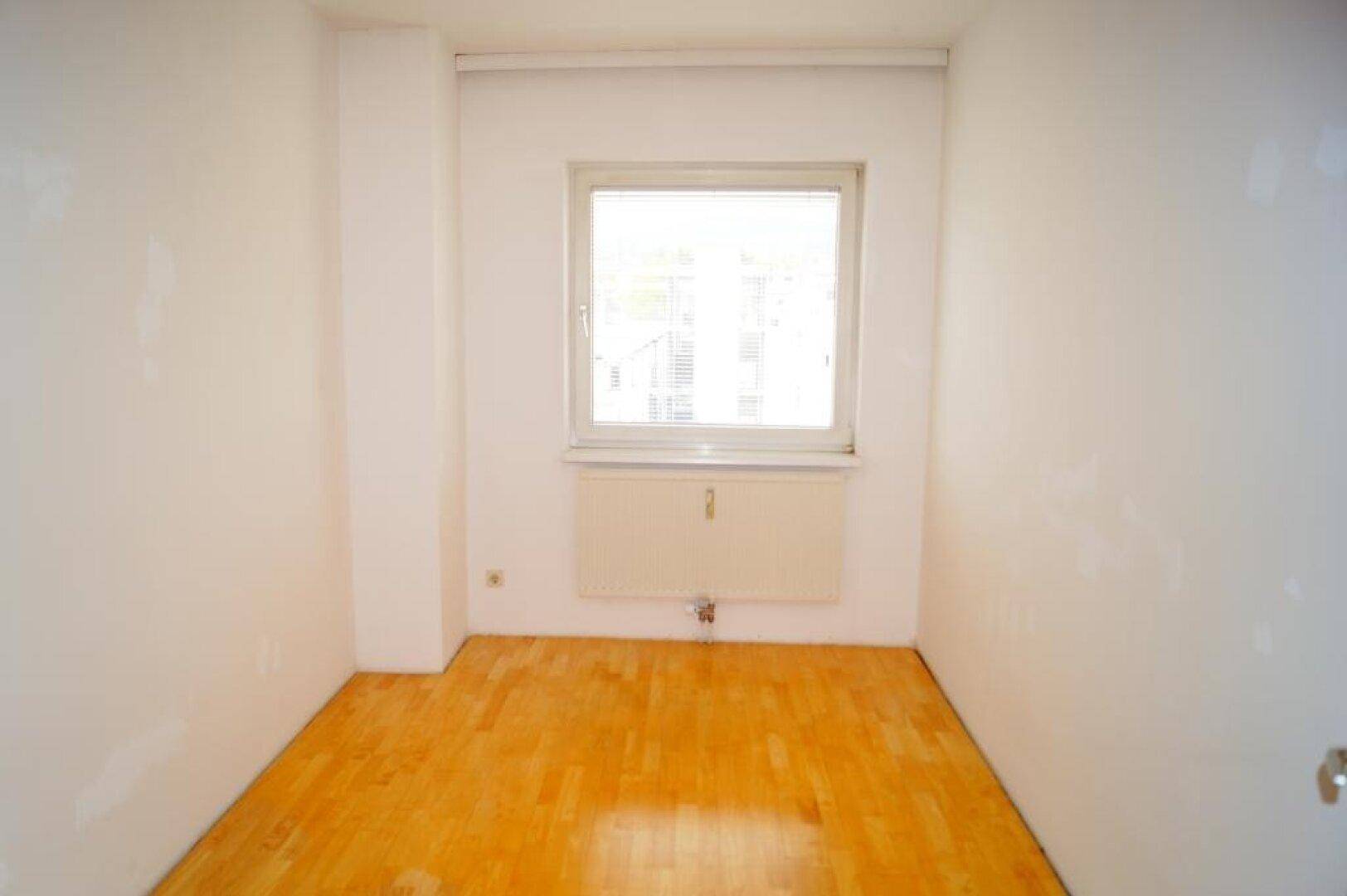 Helles, unmöbliertes Zimmer mit Parkettboden und Fenster, bereit zur individuellen Gestaltung.