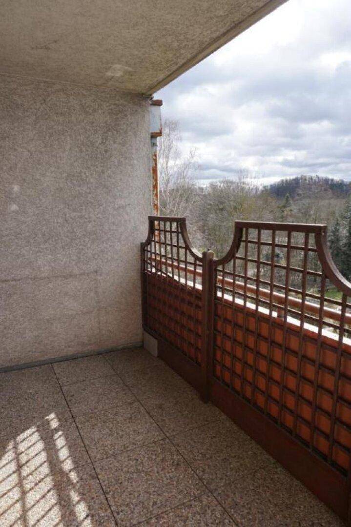 Balkon mit Fliesenboden und Holzgitter, bietet einen weiten Blick ins Grüne.