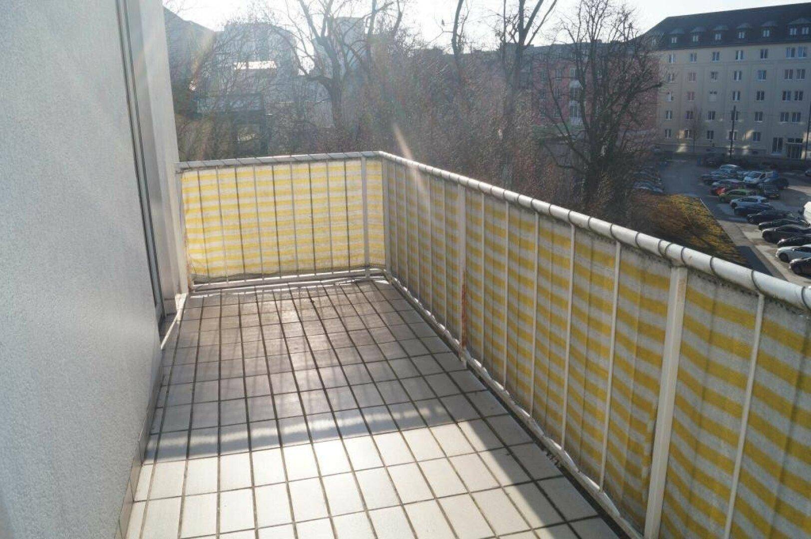 Heller Balkon mit Fliesenboden und Blick auf die Umgebung, ideal für sonnige Stunden.