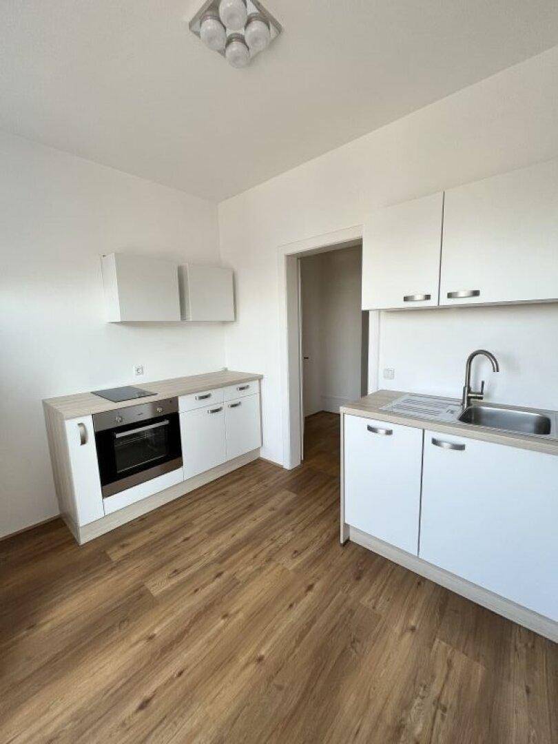 Kompakte Küchenzeile mit integriertem Backofen, Kochfeld und Spülbereich in hellem Design.
