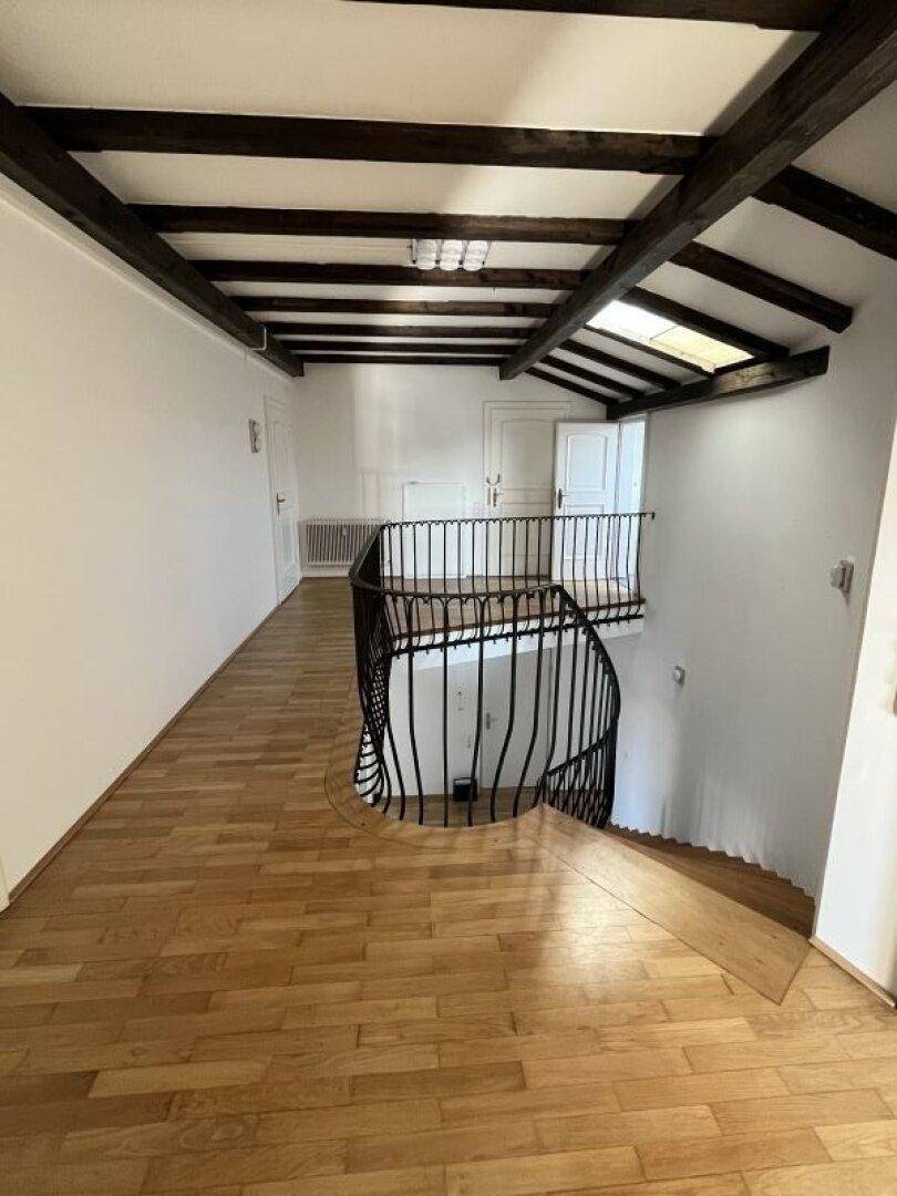Flur mit offener Treppe, Holzparkett und sichtbaren Deckenbalken, die rustikalen Charme verleihen.