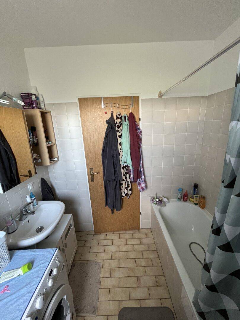 Badezimmer mit Badewanne, Waschbecken und Fliesenboden in hellem Beige.