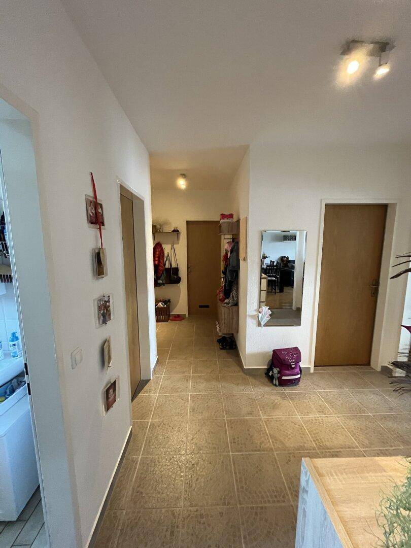 Langer Flur mit Fliesenboden, Garderobe und Spiegel.