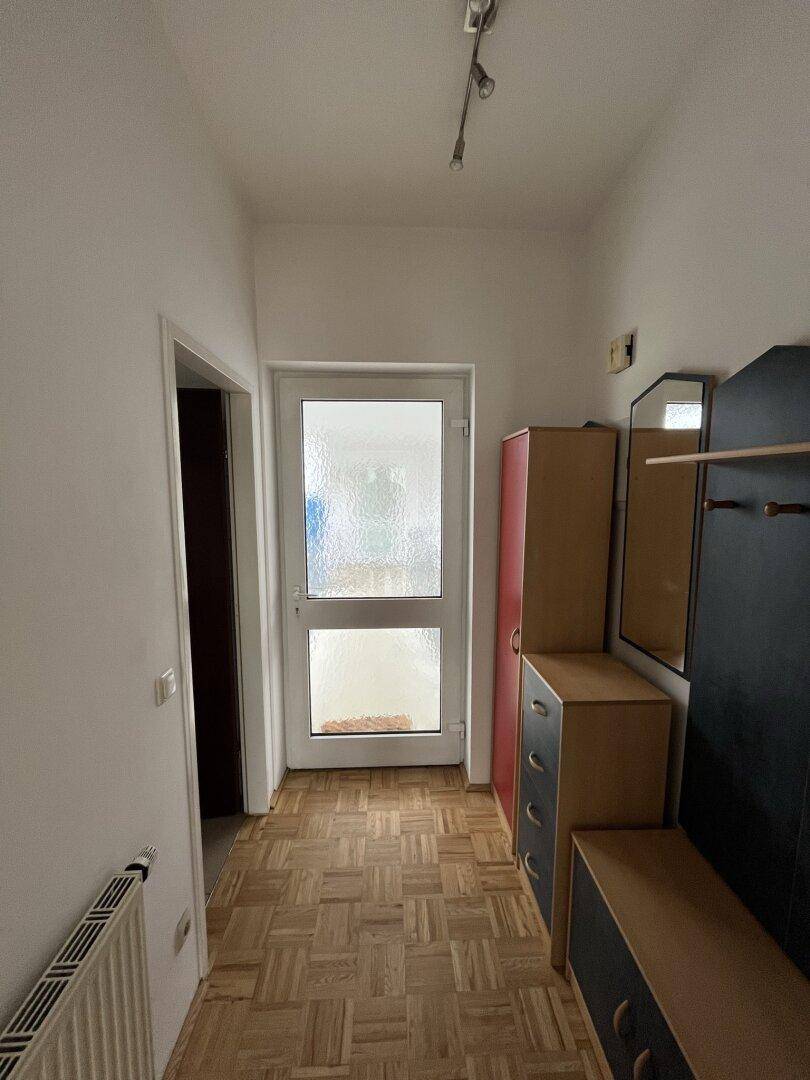 Flur mit Parkettboden, Garderobe und einer Tür zum Außenbereich, bietet praktischen Stauraum.