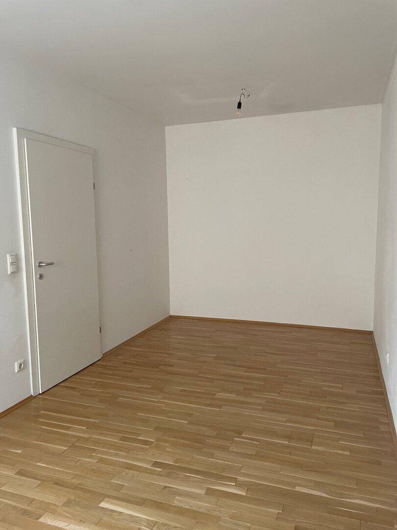 Leerer Raum mit Holzboden und einer Tür, bereit für individuelle Einrichtung.